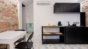 A compact kitchen with a white table, black chairs, a black cabinet, and a tiled floor. - Dimora al Cristo Velato By Dimorra (Napoli)