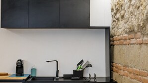 A modern kitchen with a black countertop, a coffee machine, a sink, and a knife block. - Dimora al Cristo Velato By Dimorra (Napoli)