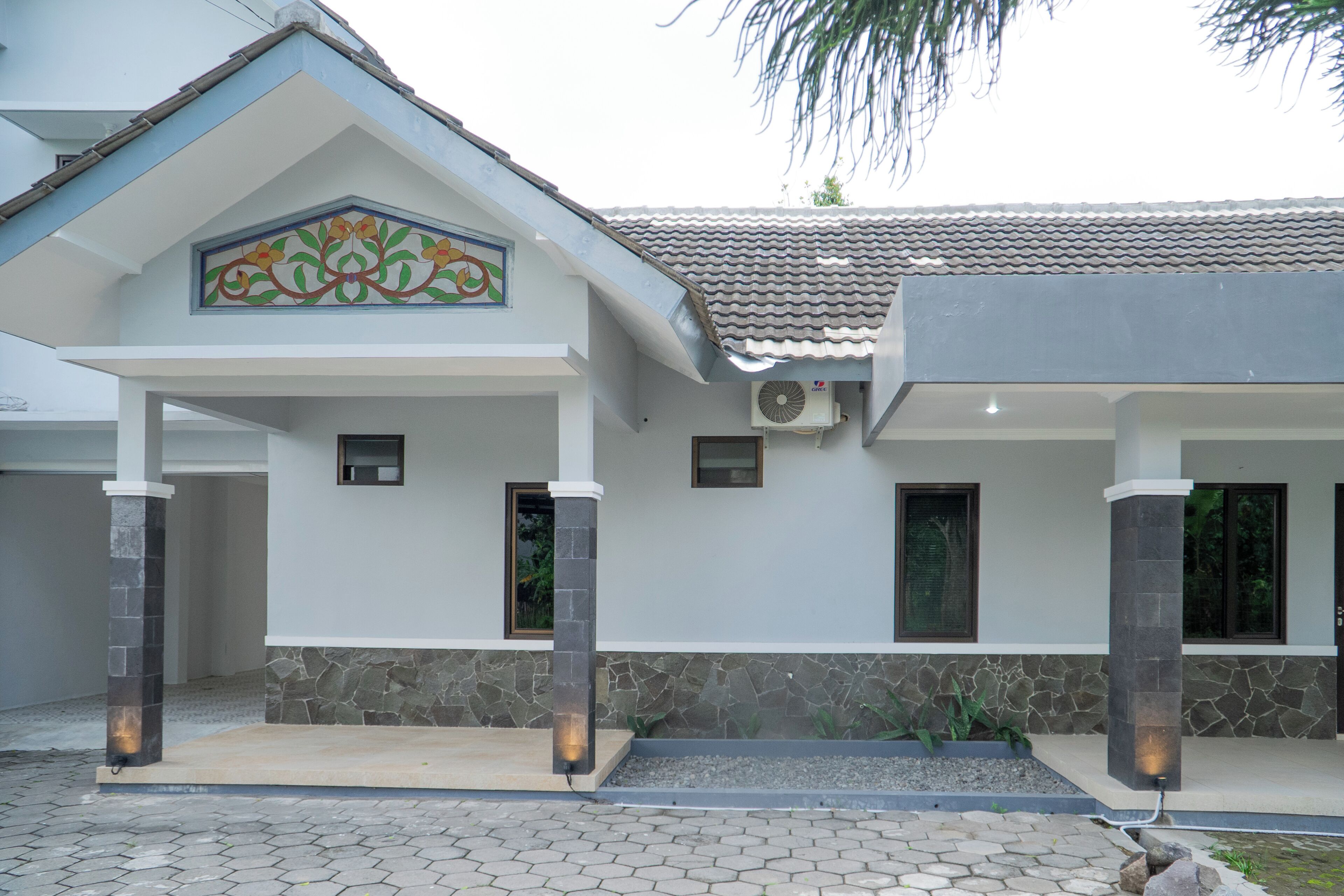 A modern building with a tiled roof, stone pillars, and a decorative tile design above the entrance.