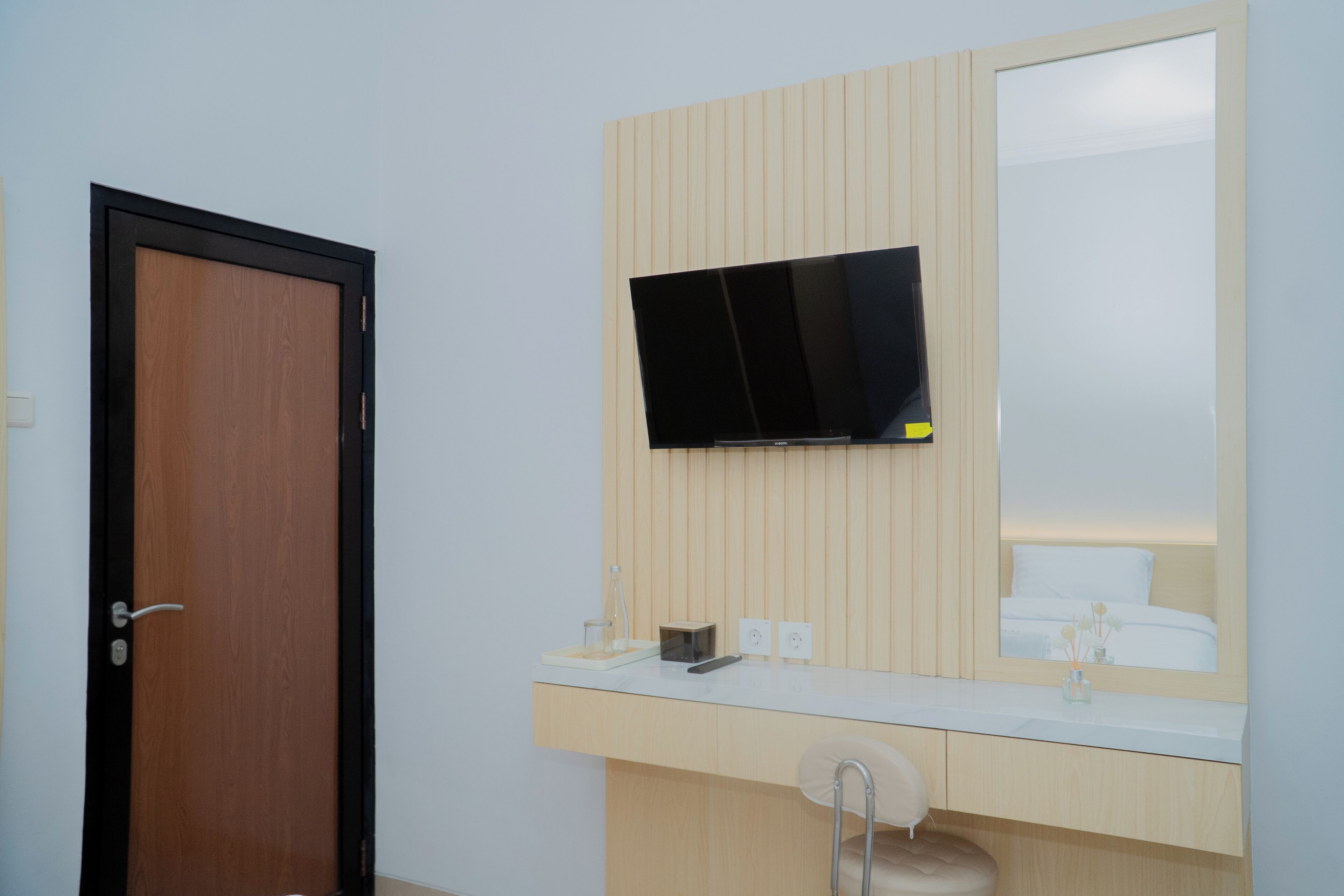 A modern bathroom with a wooden vanity, a mounted TV, and a large mirror.