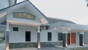 Una casa moderna con porche cubierto, detalles de piedra y un azulejo decorativo sobre la entrada.