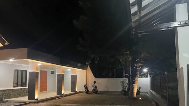 Un edificio moderno con un área exterior techada, una entrada pavimentada y una motocicleta estacionada cerca.