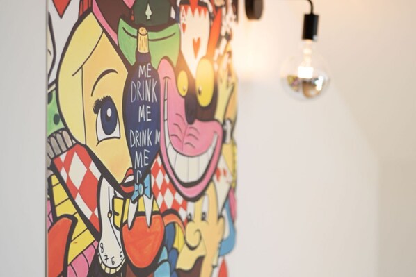 Un mural colorido con personajes de dibujos animados y la frase 'DRINK ME'.