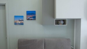 A room with a grey sofa, two framed pictures on the wall, and a globe in a shelf. - New Corte 2 By Dimorra (Napoli)