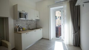 A modern kitchen with a microwave, sink, and cabinets. There is a sliding glass door leading to an outdoor area. - New Corte 2 By Dimorra (Napoli)