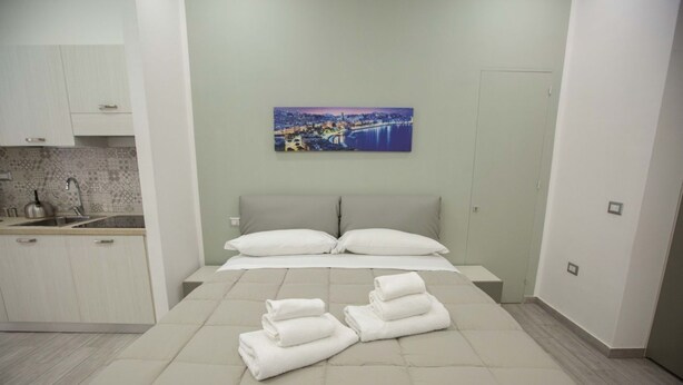 A bedroom with a bed, pillows, and neatly folded towels.