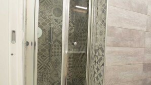 Ducha con azulejos estampados y puerta de vidrio.