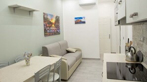 A compact living space with a kitchenette, a dining area, and a sofa. - New Corte 6 By Dimorra (Napoli)