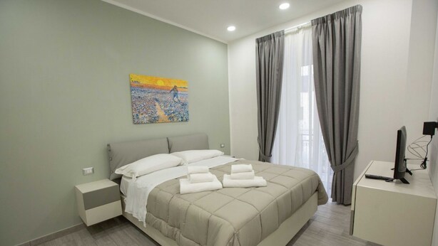 A bedroom with a bed, bedside tables, a desk with a computer, and a painting on the wall. - New Corte 6 By Dimorra (Napoli)