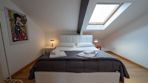 Quarto com uma cama grande, um claraboia, um quadro na parede e duas luminárias de cabeceira.