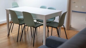 Uma área de refeições moderna, com uma mesa branca e quatro cadeiras.