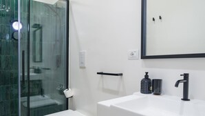A modern bathroom with a glass shower enclosure, a white sink with a black faucet, and a mirror above the sink. - Weaver Suites 1 By Dimorra (Napoli)