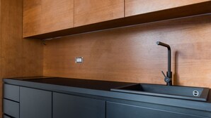 A modern kitchen with a black countertop, wooden cabinets, and a single faucet. - Weaver Suites 2 By Dimorra (NAPOLI)