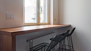 A corner of a room with a wooden ledge, a radiator, and two black chairs. - Weaver Suites 2 By Dimorra (NAPOLI)