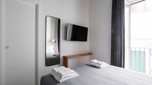 A hotel room with a bed, a TV, a mirror, and a window with curtains. - Weaver Suites 2 By Dimorra (NAPOLI)