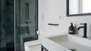 A modern bathroom with a glass shower enclosure, a white sink with a black faucet, and a mirror above the sink. - Weaver Suites 3 By Dimorra (NAPOLI)