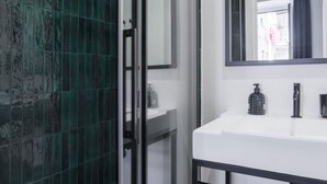 A modern bathroom with a white sink, a mirror, and a shower area with green tiles. - Weaver Suites 4 By Dimorra (Napoli)