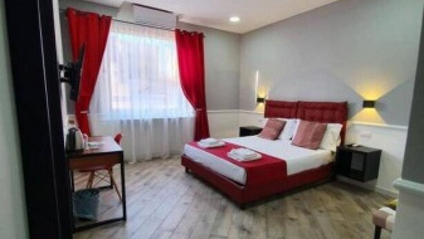 A bedroom with a bed, bedside tables, a desk, and a window with curtains. - Dimorra Boutique room 3 (Napoli)