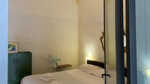 Een hotelkamer met een bed, nachtkastje, groene kast en een decoratieve plant.