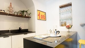 Een moderne keuken met een centraal eiland, een zwart aanrecht en een gele stoel. Op de muur staat een prijsbord van 100 euro.