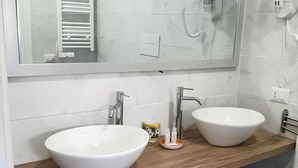 A bathroom with two white sinks, a wooden countertop, a mirror, and a towel rack.