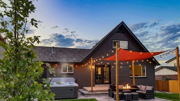 Ein modernes Haus mit Terrasse, Sitzgelegenheiten im Freien und einem Whirlpool.