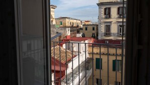 A view from a window overlooking a row of buildings with balconies and red-tiled roofs. - La Casa di Giulia By Dimorra (Napoli)