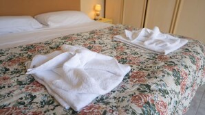 A bed with a floral bedspread and two neatly folded white towels. - La Casa di Giulia By Dimorra (Napoli)
