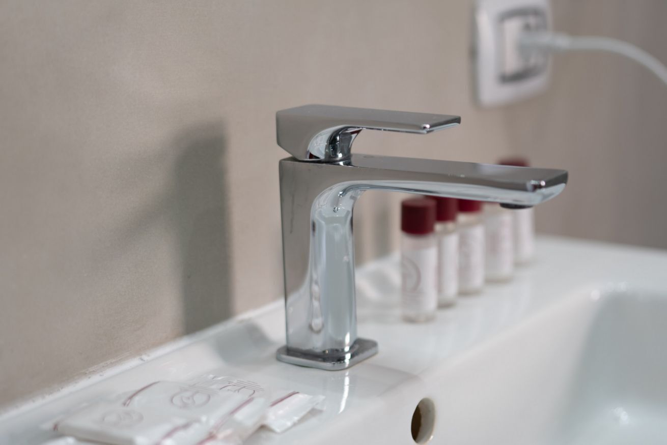 Ein Waschbecken mit Chromarmatur, einer weißen Arbeitsplatte und einer an der Wand montierten Steckdose.