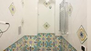 A bathroom with a tiled floor and walls, a shower area, and a towel rack.