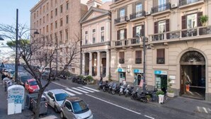 A street view of a row of multi-story buildings with parked cars and motorcycles. - King Ferdinando IV by Dimorra (Napoli)