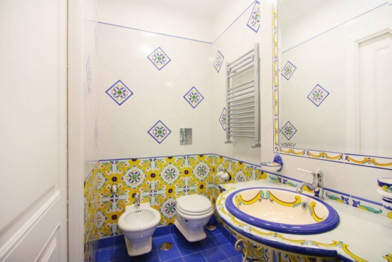 A bathroom with a white toilet, a bidet, and a sink with a blue basin.