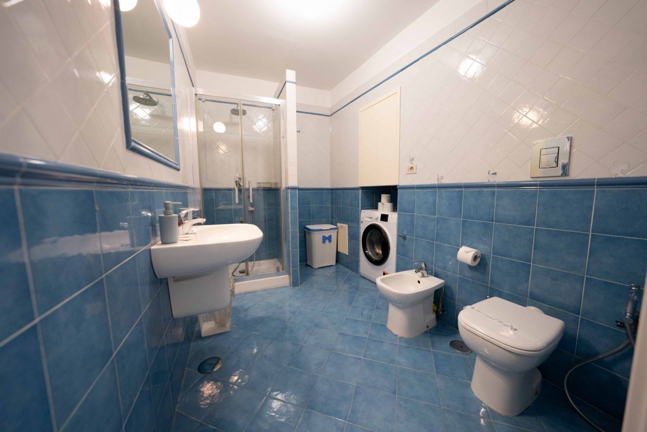 A bathroom with a sink, bidet, toilet, and washing machine.