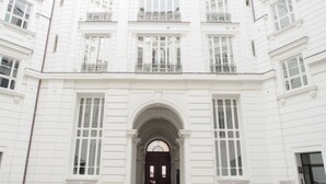 Un edificio blanco con una entrada central, ventanas amplias y balcones.