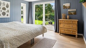 A bedroom with a bed, a wooden dresser, and a large window.