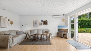 A modern living room with a wooden floor, a sofa set, a coffee table, and a TV.