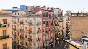 A multi-story building with balconies, a street in front, and a dome structure in the background. - Mare Fiore Room By Dimorra (Napoli)