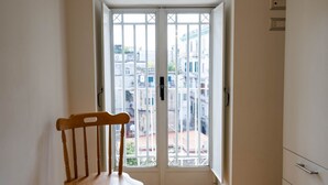 A room with a wooden chair, a white door with glass panels, and a view of buildings outside. - Andreas Home By dimorra (Napoli)
