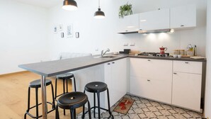 A modern kitchen with a central island, bar stools, white cabinets, and pendant lighting. - Andreas Home By dimorra (Napoli)