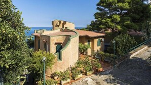 A Mediterranean-style building with a curved roof, a small balcony, and a view of the sea.