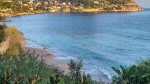 A coastal landscape with a prominent rocky island and a beach in the foreground.