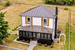 A two-story house with a sloped roof, a covered porch, and a fenced yard. - Modern Farmhouse w/ Hot Tub, Close to SNP (Shenandoah)