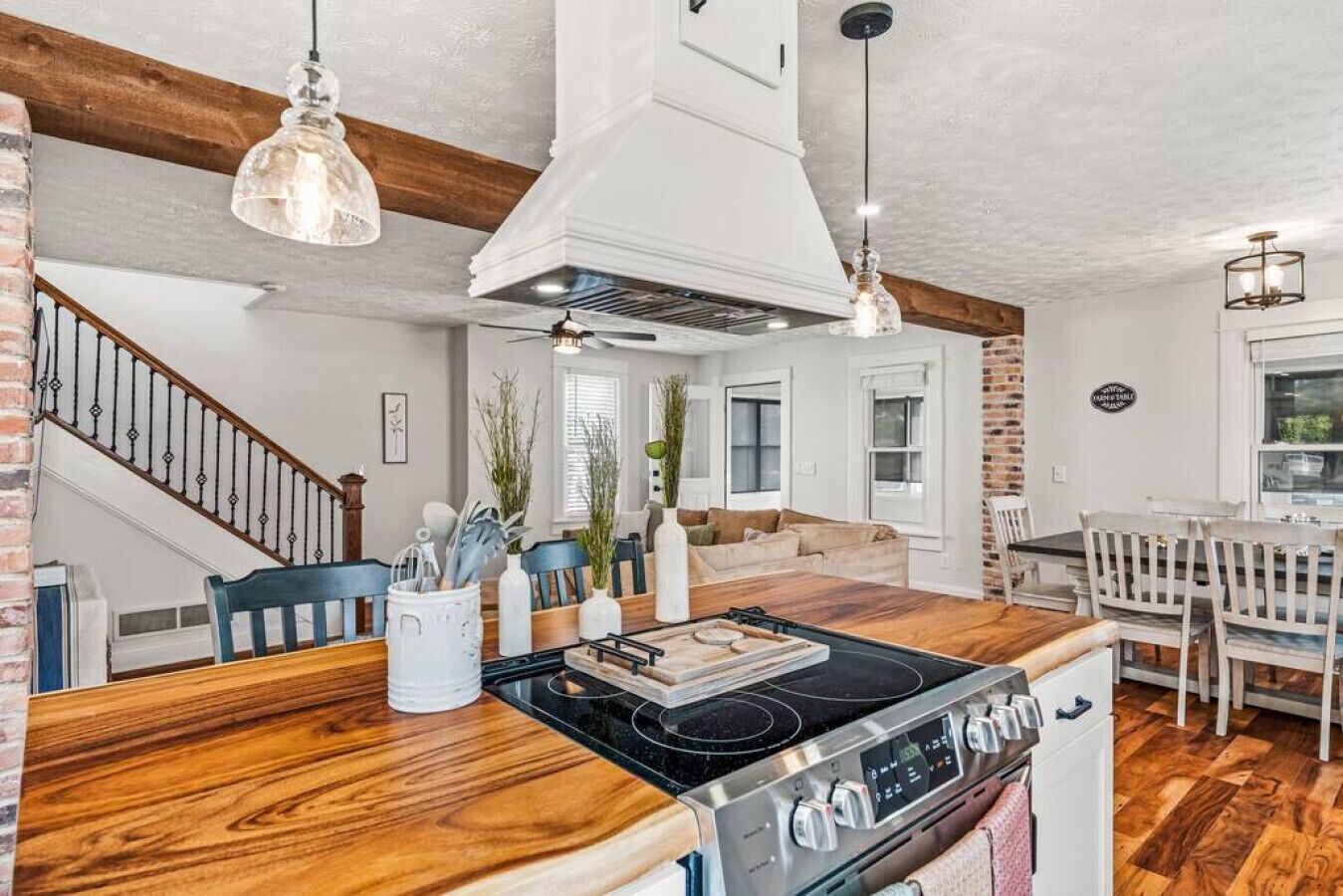 Une cuisine moderne dotée d’un îlot central, de planchers en bois et d’un escalier menant à un autre niveau.