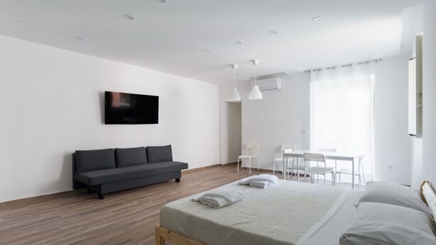 Un dormitorio moderno con una cama grande, un sofá, un escritorio y un televisor.