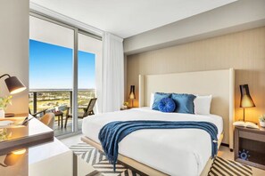 A hotel room with a large bed, a desk, a chair, a nightstand, and a view of the city. - Great APT w/ Stunning Views & Beach Access (Hollywood)