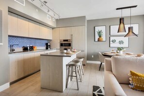 Une cuisine moderne dotée d’un îlot central, de tabourets de bar et d’un coin repas avec une table et des chaises.