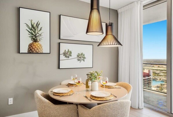 A dining area with a round table, two chairs, and a view of a cityscape through a large window. - Great Apartment Near Beach - Swimming pool (Hollywood)