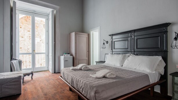 Een slaapkamer met een bed, een stoel, een kledingkast en een bureau.