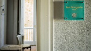 Een kamer met een muurbevestigd bord in teal met de tekst 'San Gregorio room' en een QR-code.
