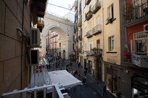 A narrow street with buildings on both sides, a white tent in the middle, and balconies with plants. - Privilege Chiaia by Dimorra (Napoli)